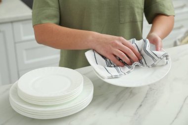 Mutfaktaki beyaz mermer masaya havluyla silen kadın, yakın plan.