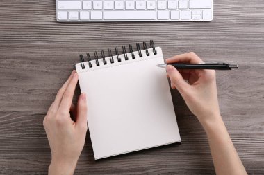 Ahşap masada deftere yazı yazan kadın, üst görünüm