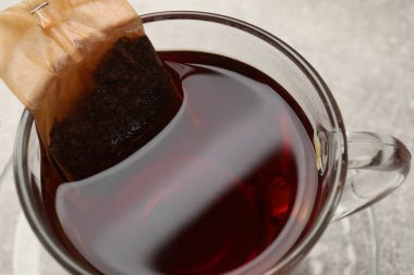 Çay demliyorum. Cam bardakta çay poşeti, yakın plan.