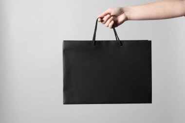 Gri arkaplanda kağıt poşet tutan kadın, yakın plan.