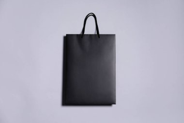 Gri arka planda bir siyah kağıt alışveriş çantası, üst manzara.