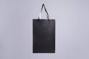Gri arkaplanda bir siyah kağıt alışveriş çantası