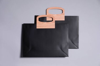 Gri arka planda iki siyah kağıt alışveriş torbası, üst manzara.