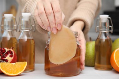 Beyaz masada ev yapımı mayalanmış kombu çayı yapan kadın, yakın plan.