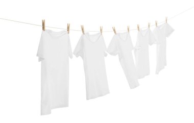 Çamaşır ipinde kuruyan birçok tişört beyaza izole edilmiş.