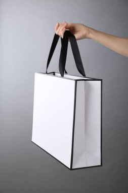 Gri arka planda kağıt poşet tutan kadın, yakın plan. Tasarım için model