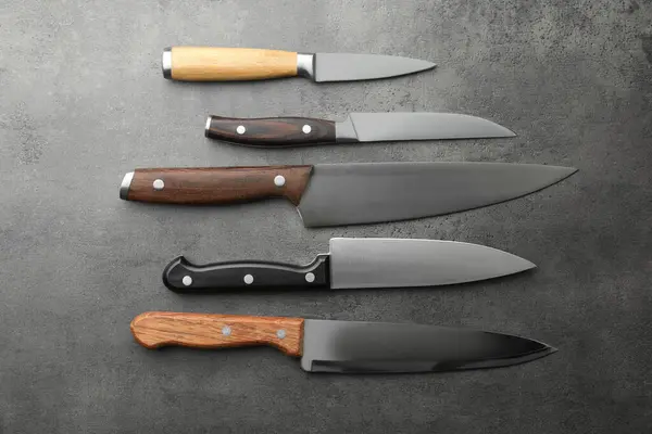 Gri desenli masa üzerinde birçok farklı bıçak, düz yatıyordu.