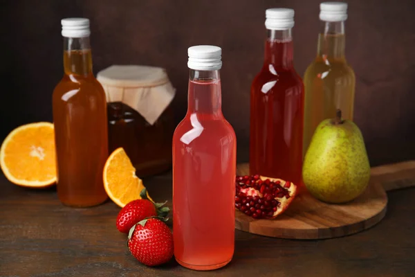 Stock image Delicious kombucha in glass bottles, jar and fresh fruits on wooden table