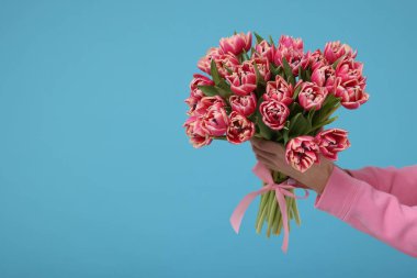 Açık mavi arka planda güzel bir buket tutan kadın, yakın plan. Metin için boşluk