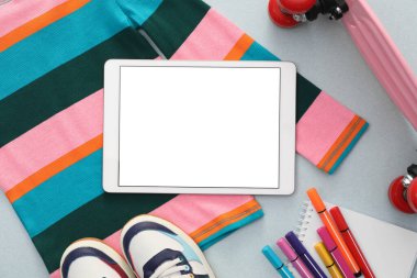 Modern tablet, giysi ve arkaplanda kırtasiye malzemesi, düz bir zemin. Metin için boşluk