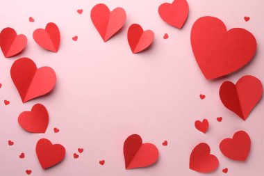 Pembe zemin üzerinde güzel kırmızı kağıt kalpler çerçevesi, düz yatıyordu. Metin için boşluk