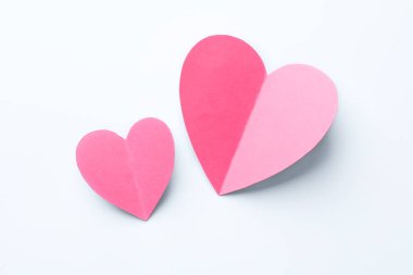 Beyaz zemin üzerinde pembe kağıt kalpler, düz uzanmış