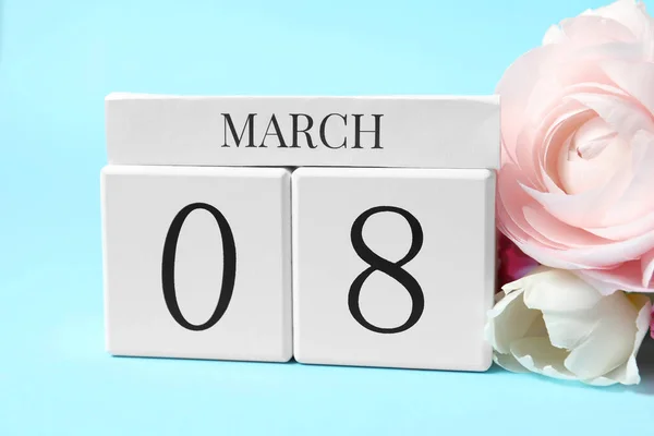 International Women\'s day - 8th of March. Wooden block calendar and beautiful flowers on light blue background