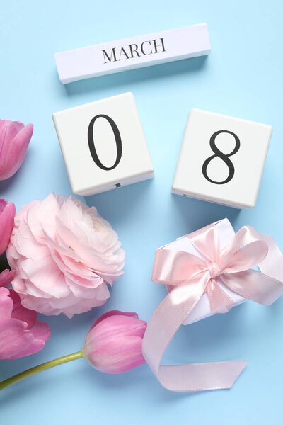 Международный женский день - 8 марта. Подарочная коробка, деревянный календарь и красивые цветы на светло-голубом фоне, плоская кладка