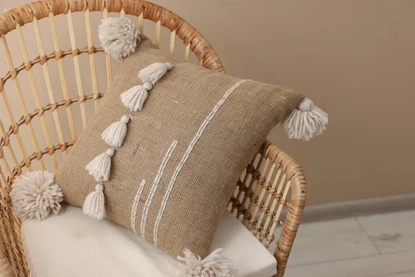 Stylish soft pillow on armchair near beige wall indoors