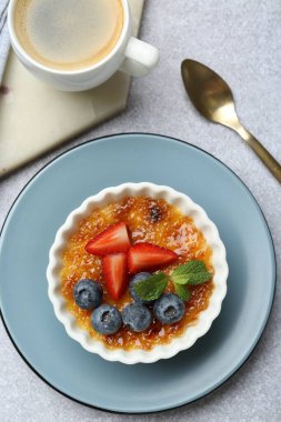 Böğürtlenli ve nane şekerli leziz creme brulee gri desenli masada servis edilir.