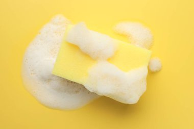 Sarı arka planda köpüklü sünger, üst görünüm