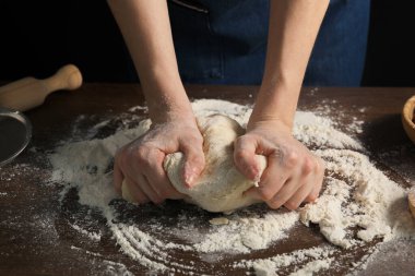 Ekmek yapıyorum. Ahşap masada hamur yoğuran kadın, yakın plan.