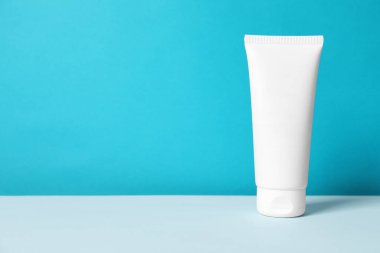 Masanın üzerinde açık mavi arkaplana karşı el kremi tüpü, metin için boşluk
