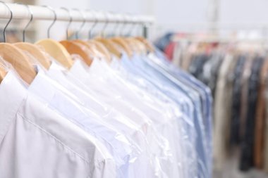 Kuru temizleme servisi. Plastik poşetlerdeki birçok farklı giysi kapalı yerlerde asılı, yakın plan.