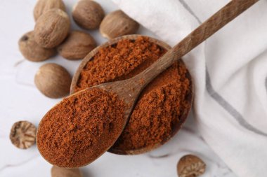 Nutmeg tozu ve tohumlar beyaz masada, düz yerde.