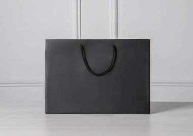 Siyah kağıt torba beyaz tahta masada.