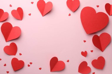 Pembe zemin üzerinde güzel kırmızı kağıt kalpler çerçevesi, düz yatıyordu. Metin için boşluk