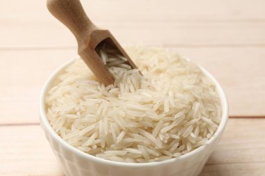 Çiğ basmati pilavı ve kepçeyle beyaz ahşap masa, yakın plan.