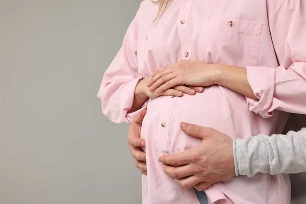 妊娠中の妻の腹を軽い灰色のバックグラウンドで触った男 クローズアップ テキスト用スペース — ストック写真