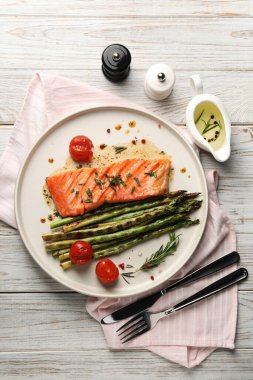 Lezzetli ızgara somon, domates, kuşkonmaz ve baharatlar masada servis edilir.