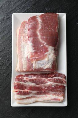 Siyah desenli masa üzerinde çiğ domuz göbeği parçaları.