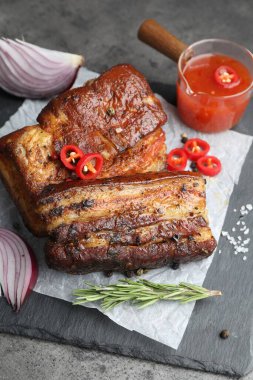 Fırında domuz göbeği, sos, biberiye ve biberiye ile servis edilmiş gri masada.