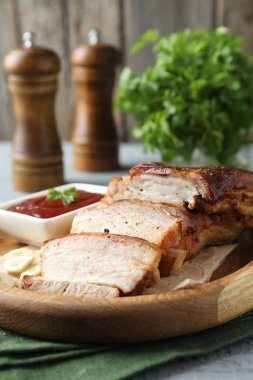 Gri ahşap masada soslu fırında domuz göbeği parçaları.