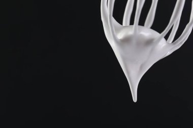 Siyah arka planda krem şantili çırpma çırpma, yakın plan. Metin için boşluk