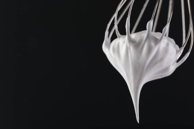 Siyah arka planda krem şantili çırpma çırpma, yakın plan. Metin için boşluk