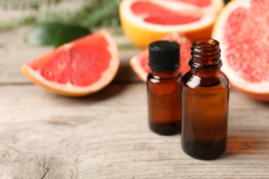 Şişelerde greyfurt yağı ve ahşap masada meyveler, yakın çekim. Metin için boşluk