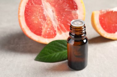 Şişede greyfurt yağı, ışık masasında yaprak ve meyve, yakın çekim