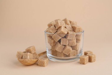 Esmer şeker küpleri cam ve kaşık bej arka planda, yakın plan