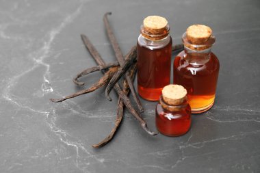 Aromatik vanilya özü ve kapsüller siyah masada. Metin için boşluk