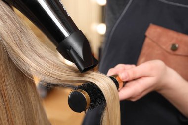 Kuaför kuaför kuaförde müşterinin saçını kurutuyor.