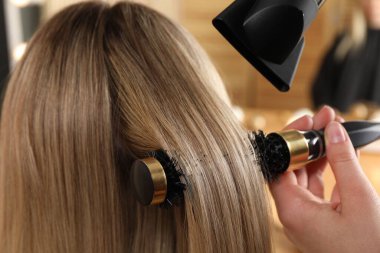 Kuaför kuaför kuaförde müşterinin saçını kurutuyor.