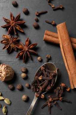 Farklı baharatlar ve kaşık koyu gri desenli masa, düz.