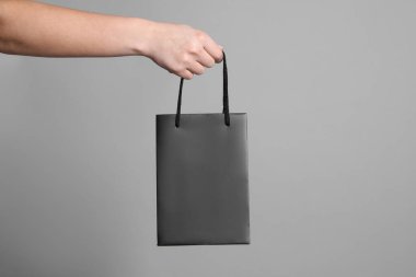 Gri arkaplanda kağıt poşet tutan kadın, yakın plan.