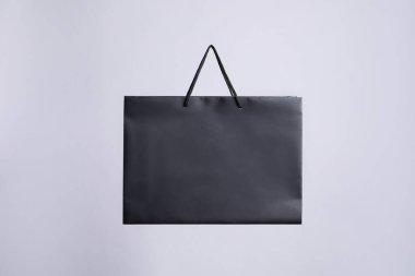 Gri arkaplanda bir siyah kağıt alışveriş çantası