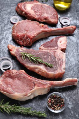 Taze çiğ et ve gri dokulu masada farklı baharatlar.