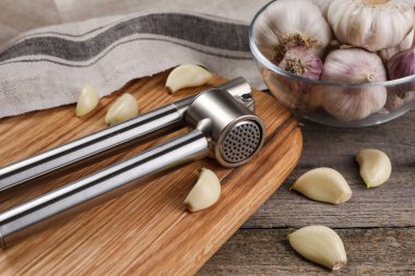 Sarımsak ezici ve karanfiller ahşap masada, yakın plan.