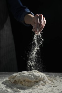 Ekmek yapıyorum. Masaya un serpiştiren bir kadın. Arka planda, yakın plan.