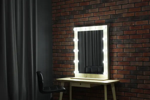 Mirror with light bulbs, table, chair and curtain in makeup room