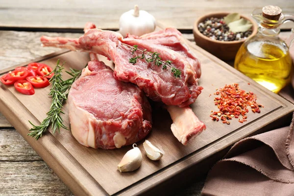 Fresh tomahawk beef cuts and spices on wooden table, closeup