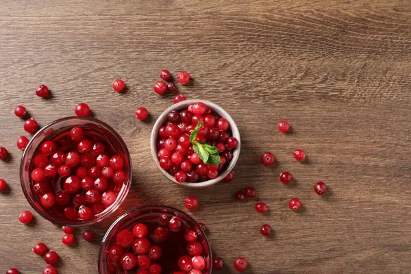 Tasty cranberry juice in glasses and fresh berries on wooden table, flat lay. Space for text